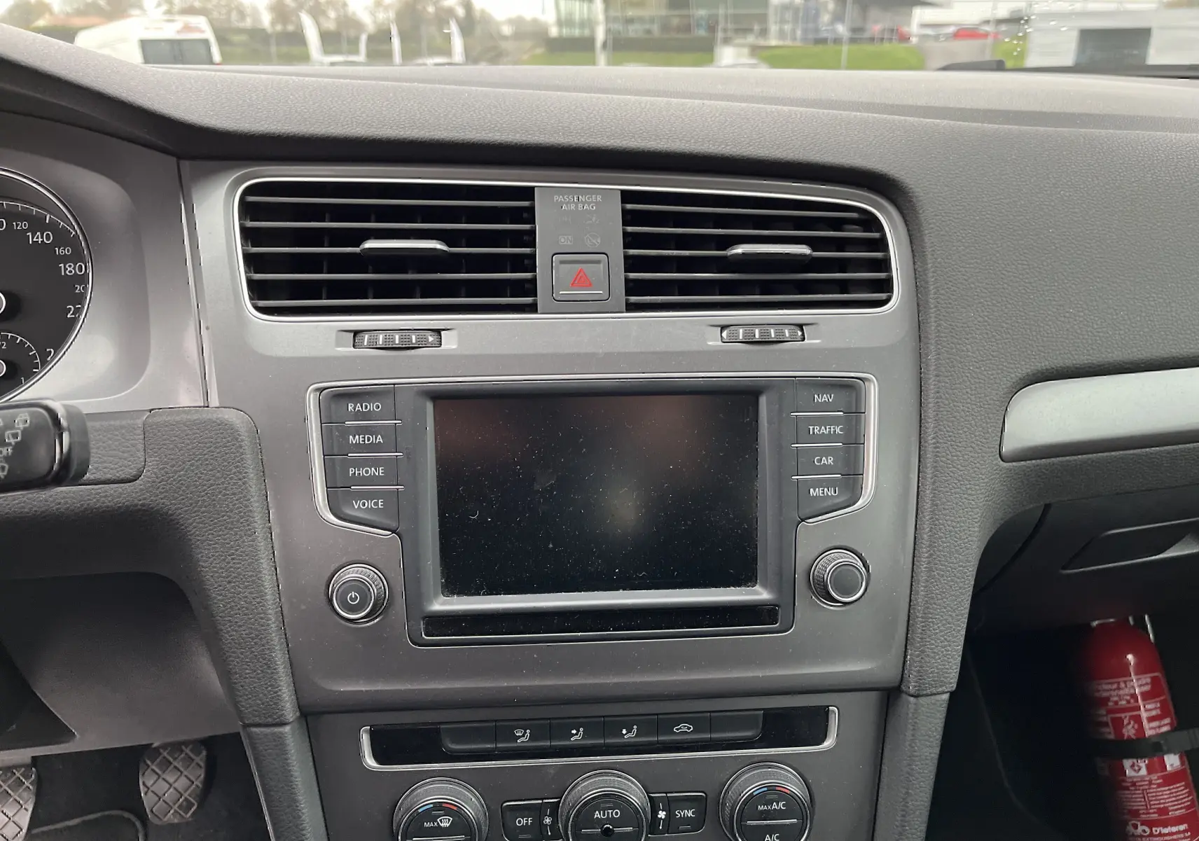 Tableau de bord noir de Volkswagen Golf 7 2017 avec écran central et commandes de climatisation visibles.