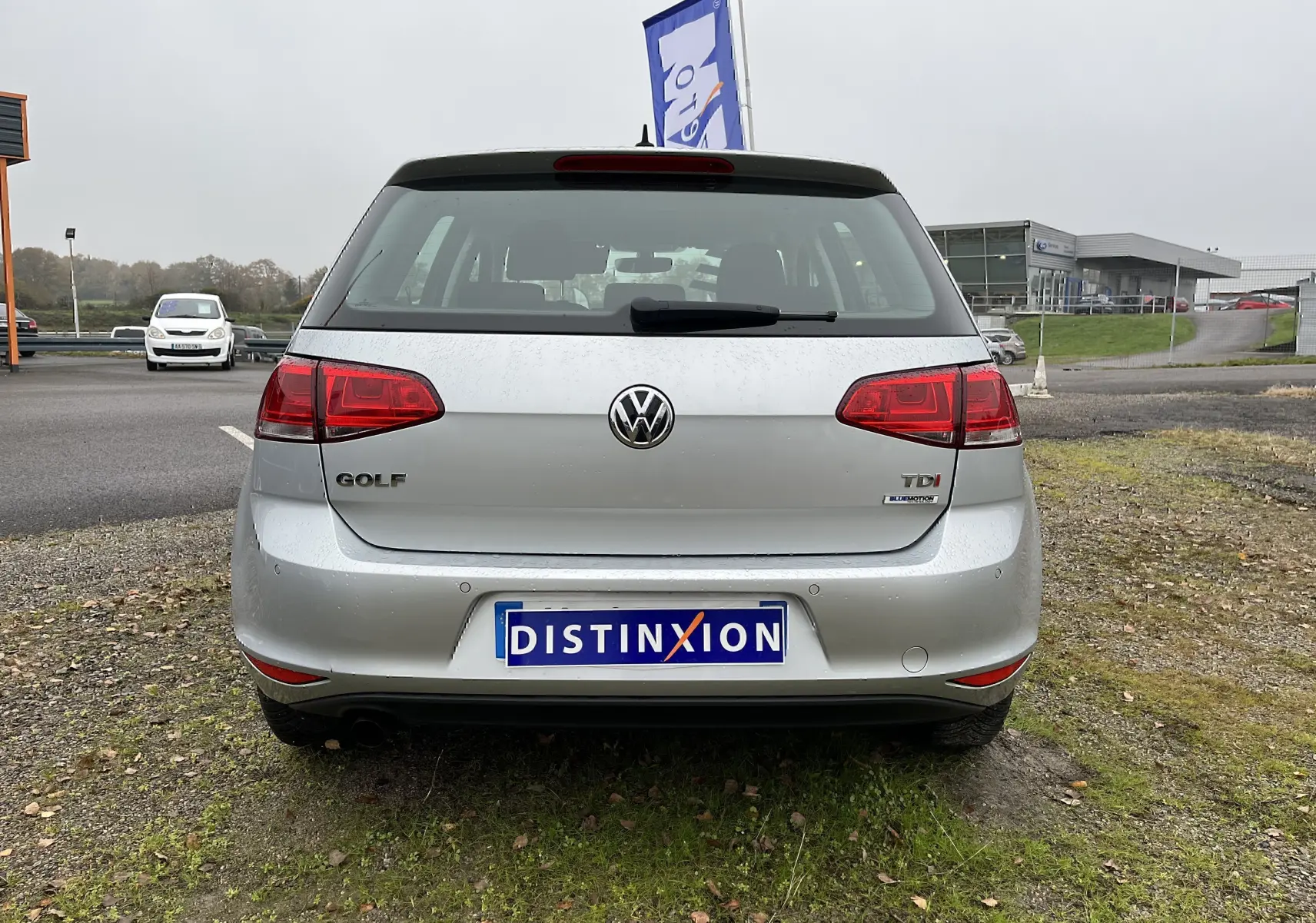 Vue arrière d'une Volkswagen Golf 7 argentée avec logo TDI et plaque Distinxion sur un parking extérieur.
