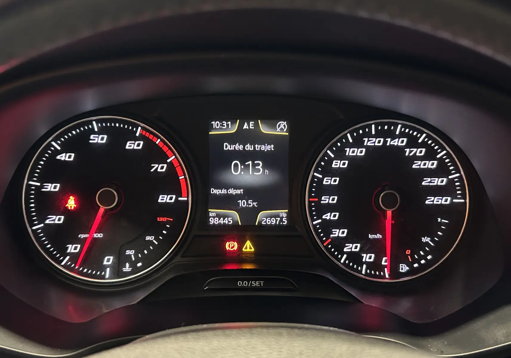 Tableau de bord du SEAT Leon 2014 noir, vue frontale des compteurs avec affichage digital central et voyants allumés.