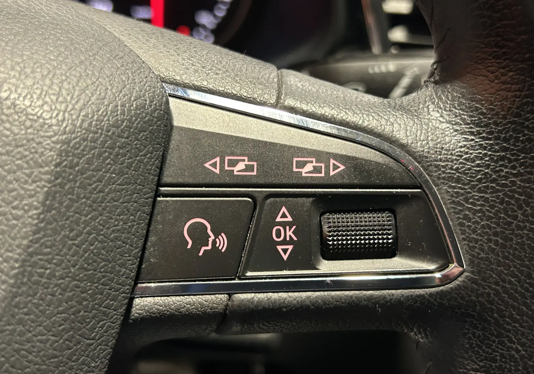 Gros plan sur les commandes multifonctions à gauche du volant noir du SEAT LEON 2014, boutons de navigation et reconnaissance vocale.