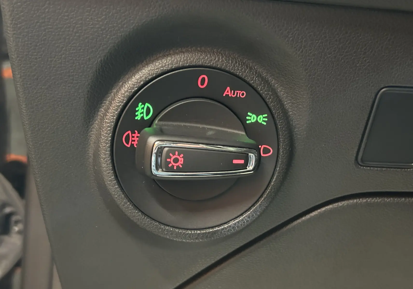 Gros plan sur le bouton de commande des phares du tableau de bord noir d'une SEAT LEON 2014.