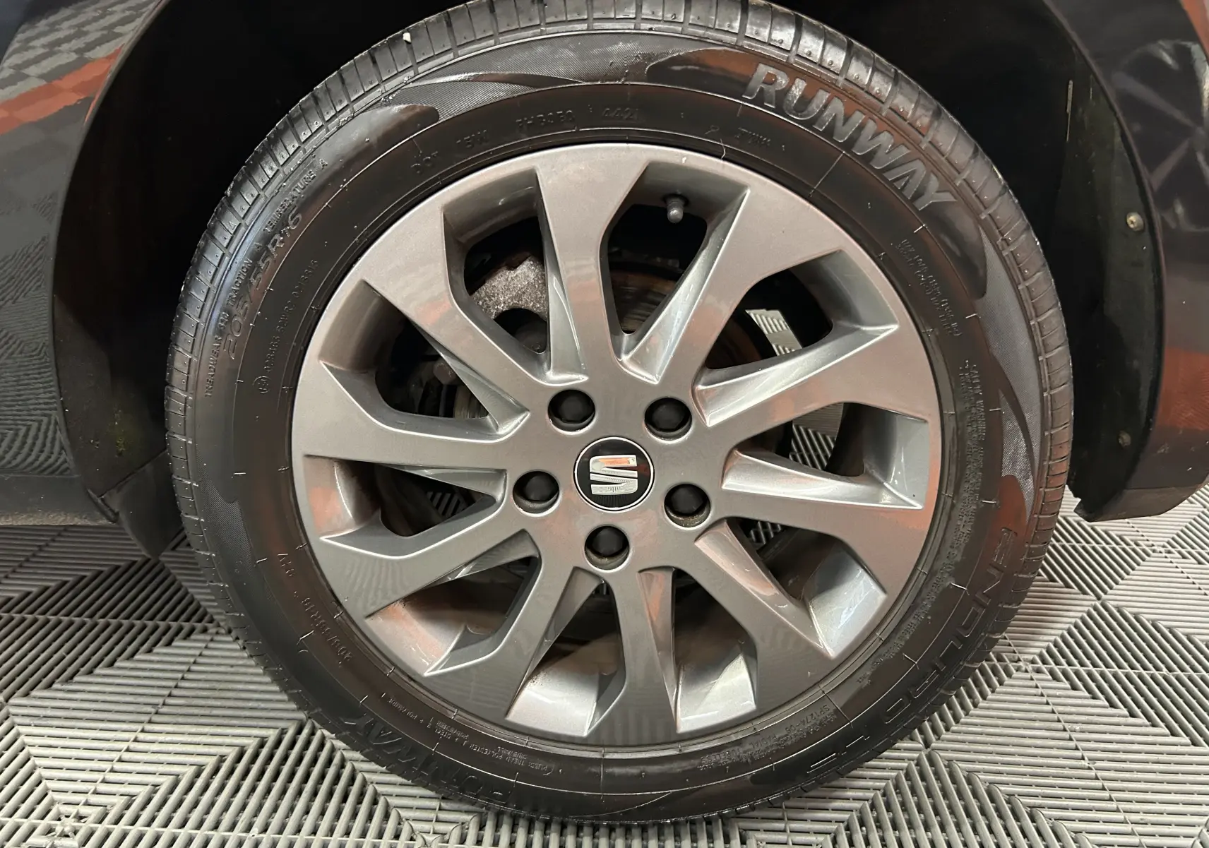 Gros plan sur la roue avant droite d’une SEAT LEON noire de 2014 avec jante alliage et pneu Runway.