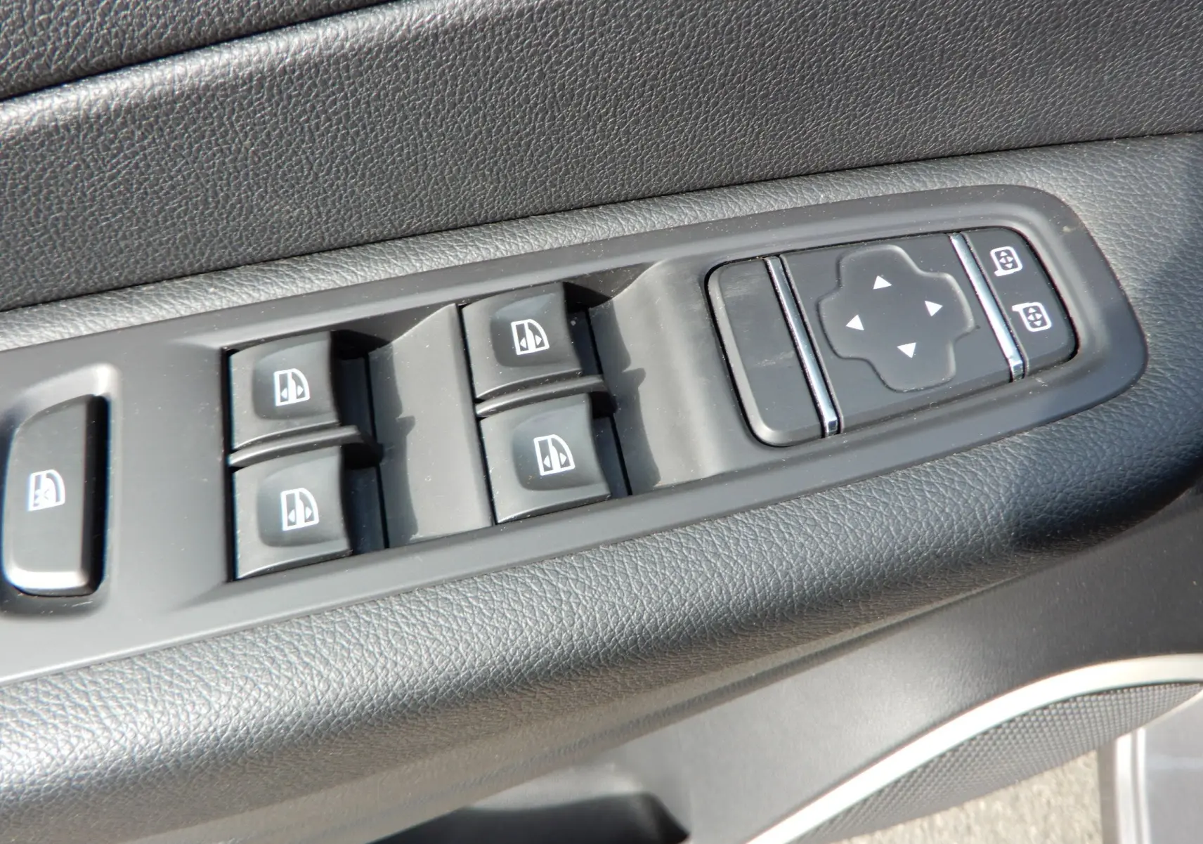 Gros plan sur les commandes de lève-vitres et réglage des rétroviseurs côté conducteur du Renault Captur gris Cassiopée.