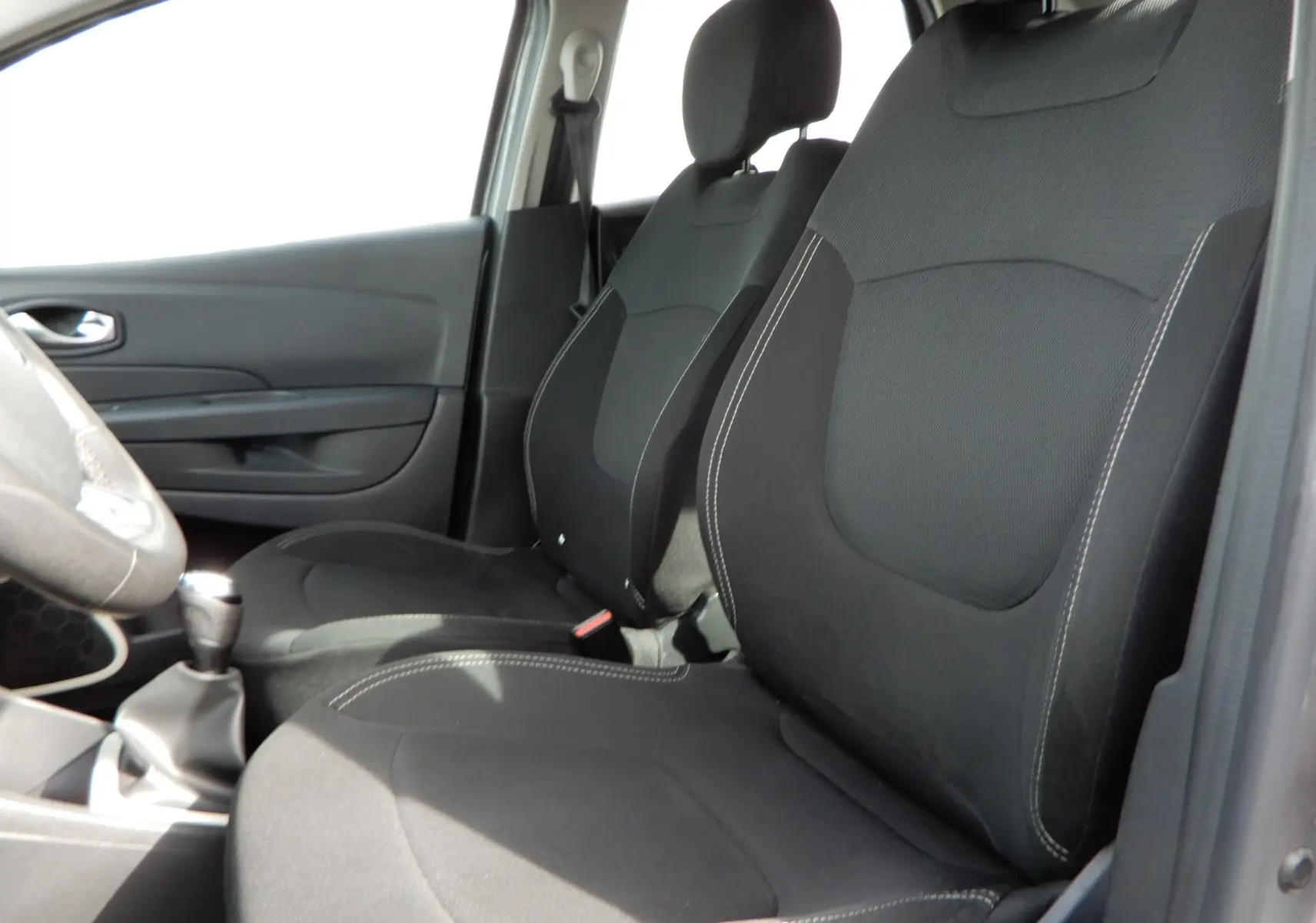 Vue intérieure côté gauche montrant les sièges avant noirs et la boîte manuelle du Renault Captur gris Cassiopée 2019.