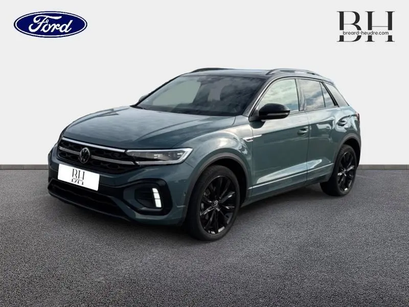 Volkswagen T-Roc bleu pétrole métallisé vu en 3/4 avant droit avec jantes noires et toit panoramique.