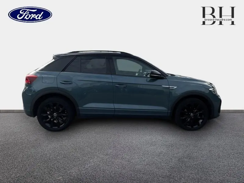 Profil droit d'un Volkswagen T-Roc 1.5 TSI R-Line 2022 bleu pétrole métallisé avec jantes noires et vitres teintées.