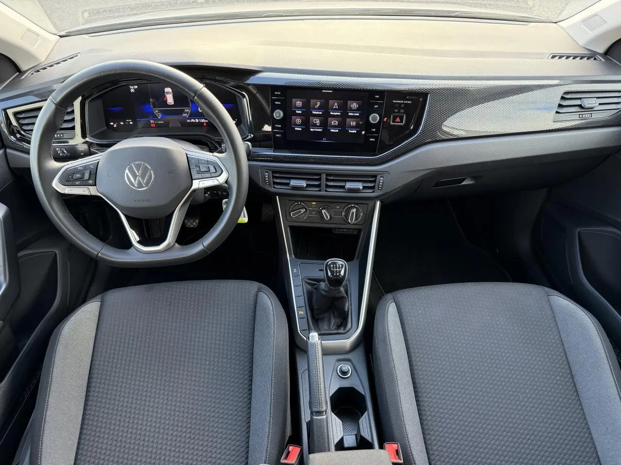 Intérieur de la Volkswagen Polo 2025 en gris, vue de face sur le tableau de bord avec volant et boîte manuelle.