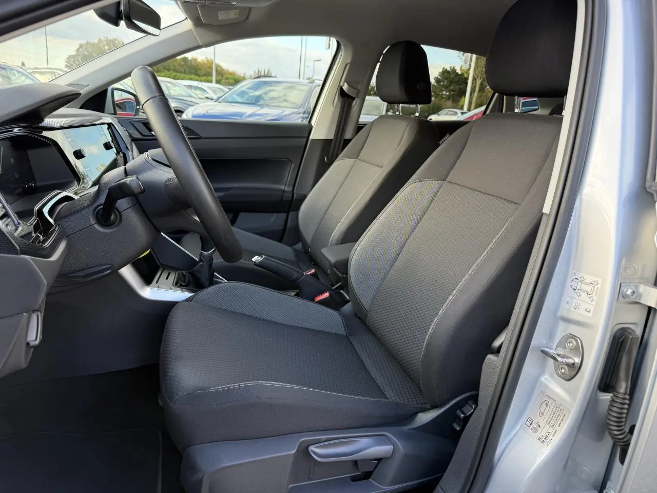Intérieur avant droit d'une Volkswagen Polo 2025 gris Reflet Argent, sièges tissu noir et tableau de bord moderne.