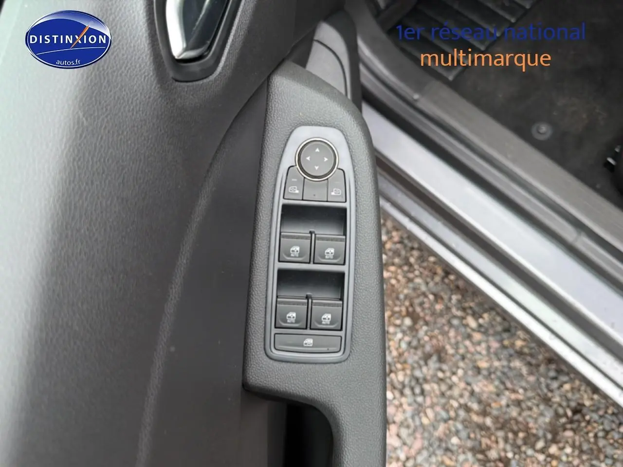 Vue rapprochée des commandes des vitres électriques sur la porte côté gauche d'une Renault Clio V gris schiste.