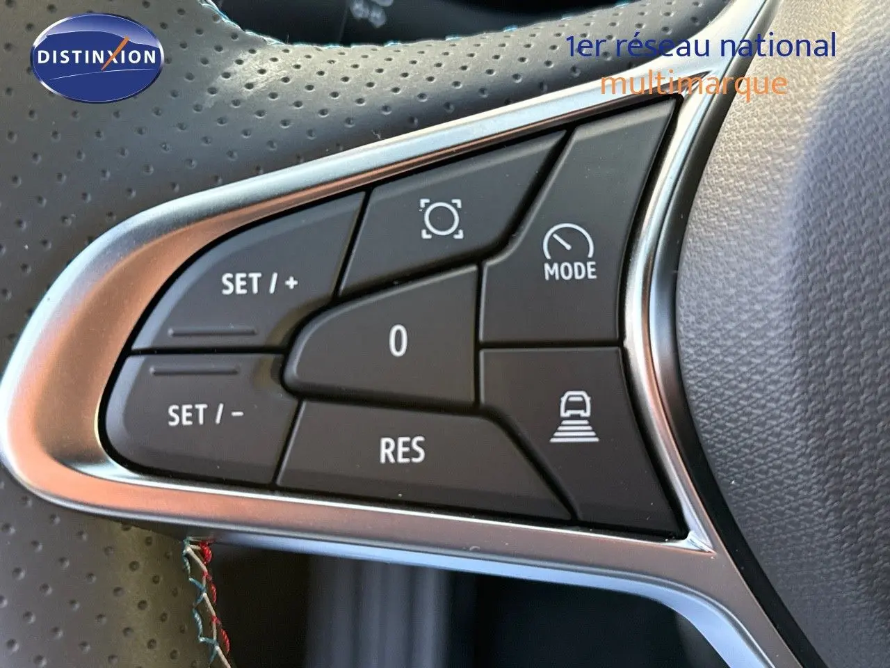 Gros plan sur les commandes de régulateur au volant en cuir perforé du Renault Symbioz gris cassiopée métal.