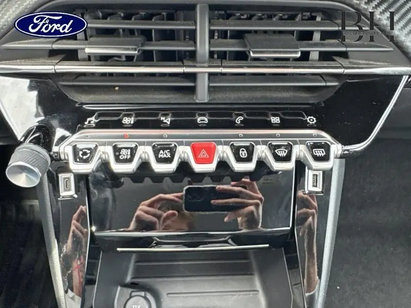 Gros plan sur la console centrale noire brillante avec boutons de commande et prises USB du Peugeot 2008 gris Artense.