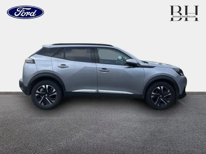 Profil côté gauche du Peugeot 2008 gris Artense avec jantes noires et toit contrasté noir visible sur fond clair.