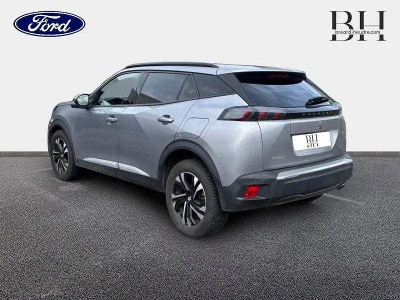 Peugeot 2008 gris Artense vue 3/4 arrière droit, avec barres de toit et feux arrière LED distinctifs.