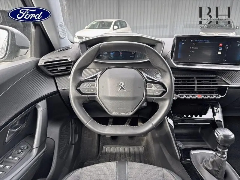 Vue intérieure du poste de conduite du Peugeot 2008 1.5 BlueHDi 2021, volant multifonction et boîte manuelle visibles.