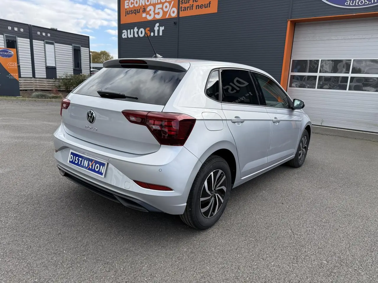 Volkswagen Polo gris Reflet Argent vue 3/4 arrière droit, vitres surteintées et jantes noires bicolores.