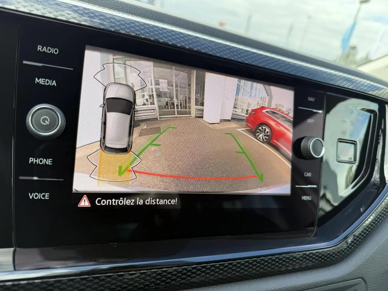 Affichage de la caméra de recul sur l'écran multimédia d'une Volkswagen Polo gris reflet argent, vue arrière avec marquages verts et rouges.