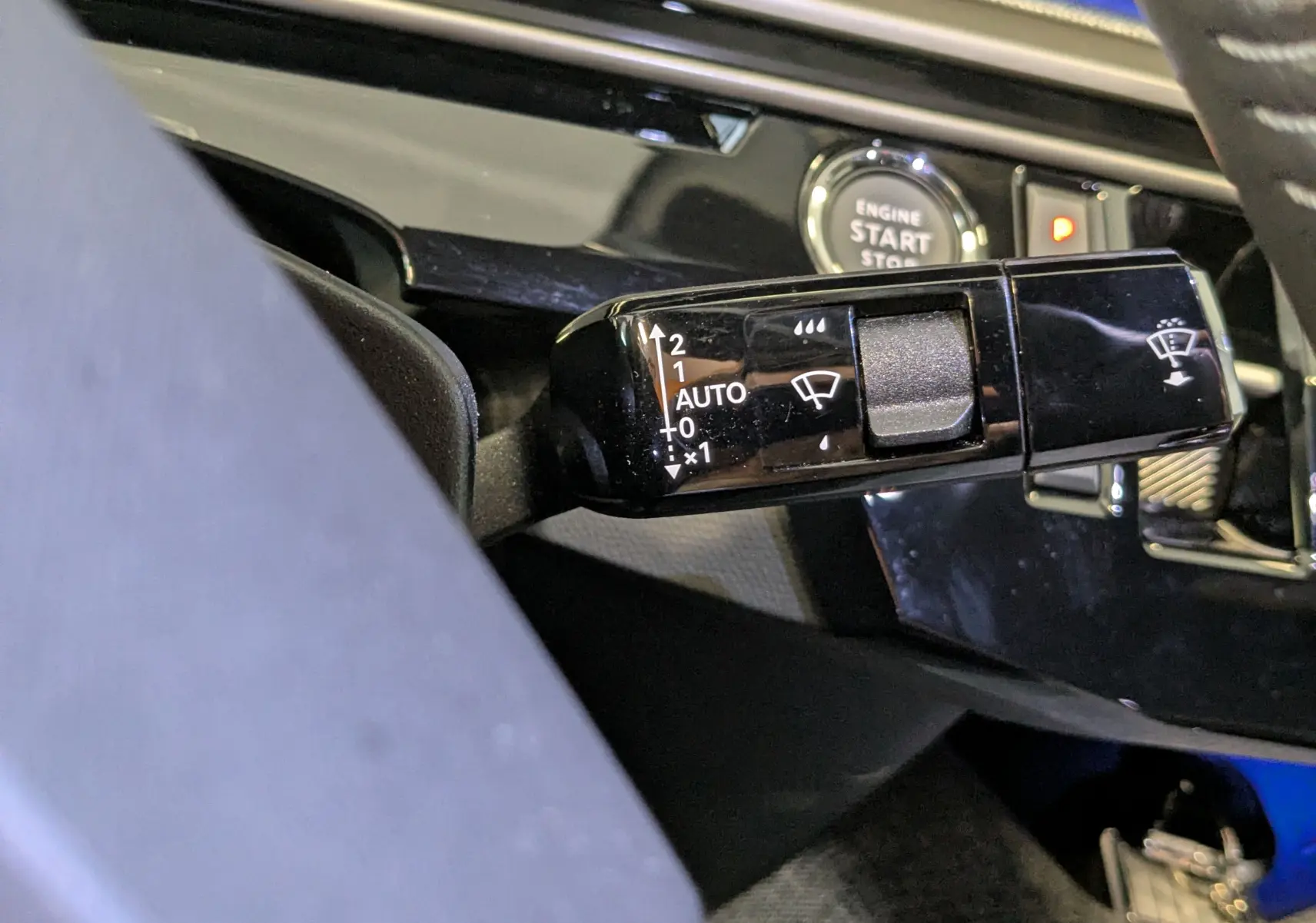 Gros plan sur la commande d’essuie-glace noire et brillante à gauche du volant dans l’habitacle du Peugeot 3008 noir 2025.