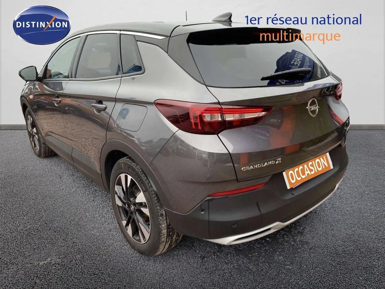 Vue 3/4 arrière droite d'un Opel Grandland X gris Moai métal avec jantes bicolores et feux LED distinctifs.