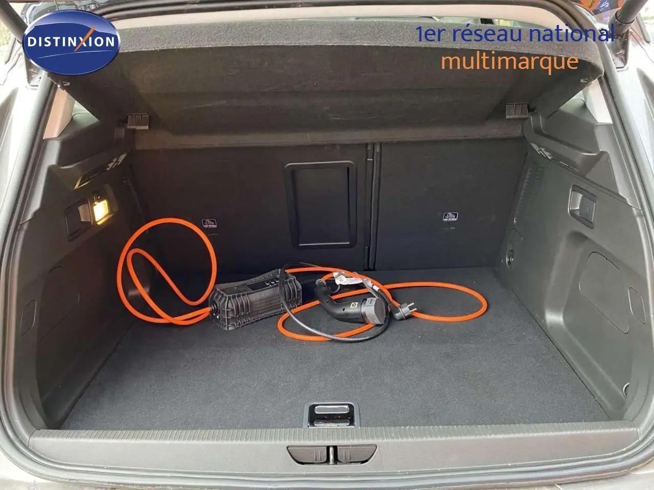 Coffre ouvert d’un Opel Grandland X gris Moai Metal avec câble de recharge hybride visible au sol.