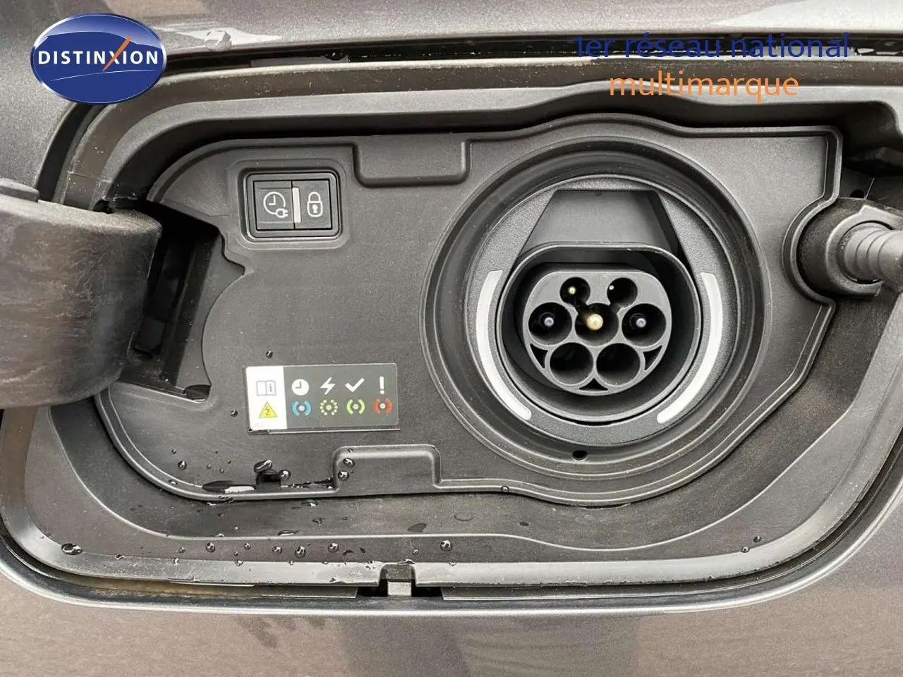 Prise de recharge hybride en gros plan sur un Opel Grandland X gris Moai Metal, montrant les connecteurs et indicateurs.