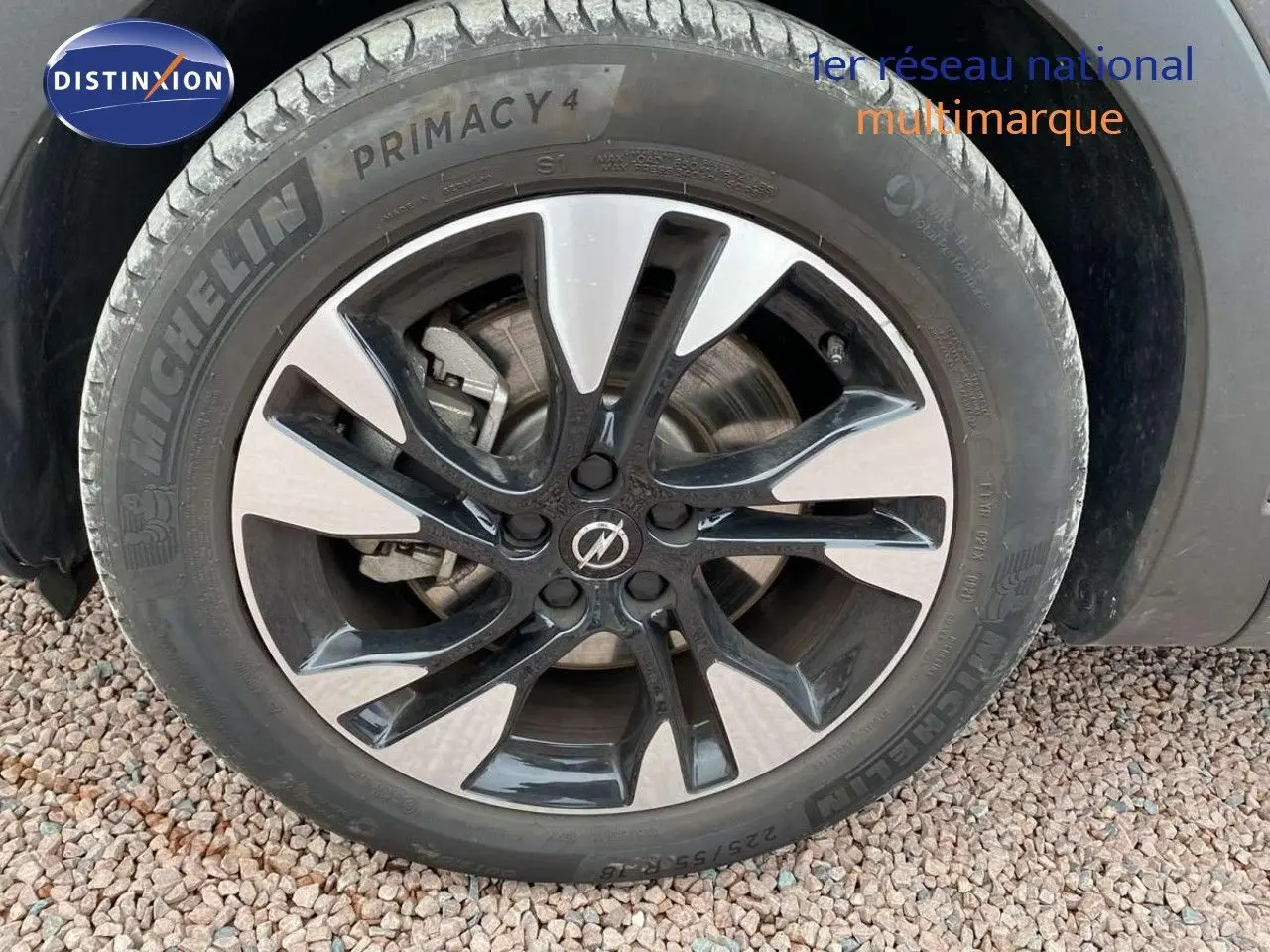 Gros plan sur la roue avant droite d'un Opel Grandland X gris Moai Metal avec jante bicolore moderne.