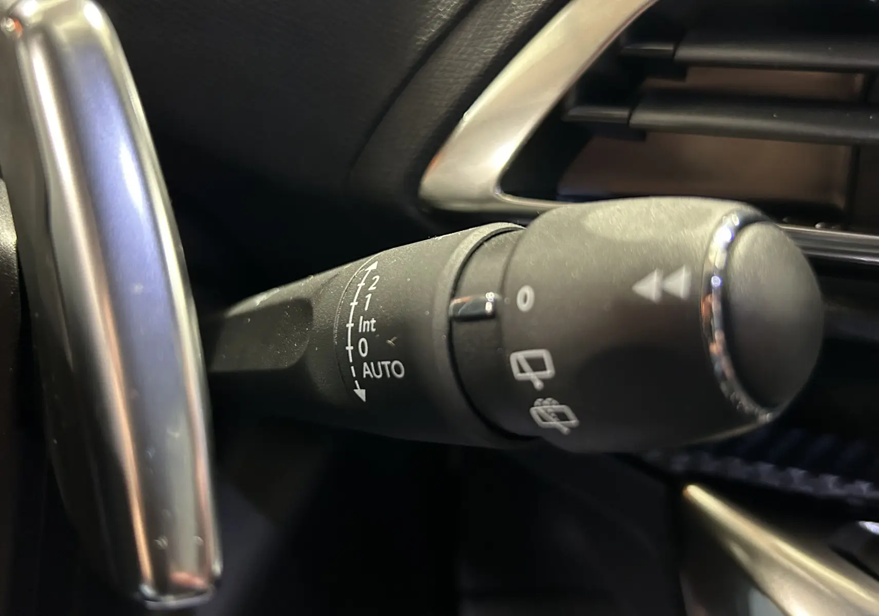 Gros plan sur la commande d'essuie-glace à gauche du volant dans l'habitacle noir du Peugeot 5008 Gris Platinium 2024.