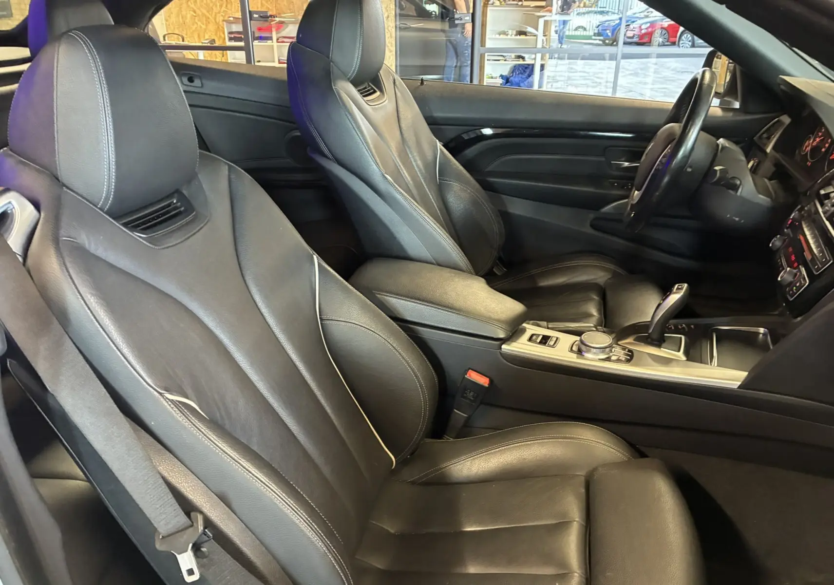 Intérieur noir cuir de la BMW Série 4 Cabriolet F33 420i, vue côté conducteur avec console centrale et volant visibles.