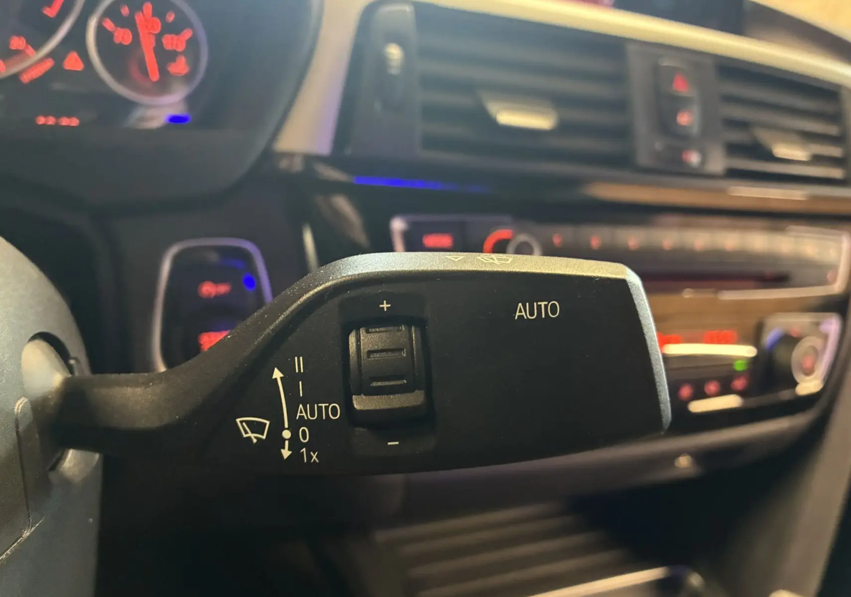 Gros plan sur la commande d'essuie-glace automatique dans l'habitacle noir d'une BMW Série 4 Cabriolet gris 2019.