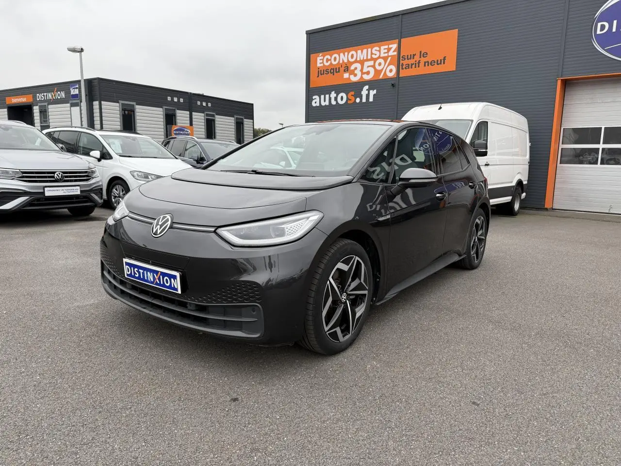 Volkswagen ID.3 Pro S gris manganèse vue 3/4 avant droit sur parking devant un bâtiment commercial