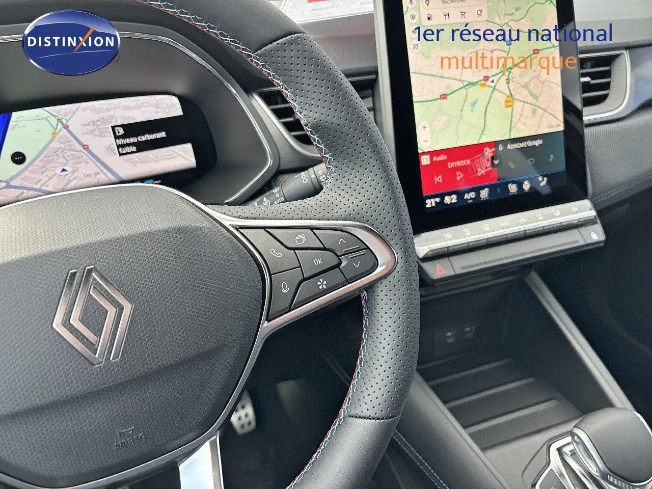 Vue rapprochée du volant en cuir perforé noir avec surpiqûres tricolores et écran tactile central du Renault Symbioz hybride 2025.