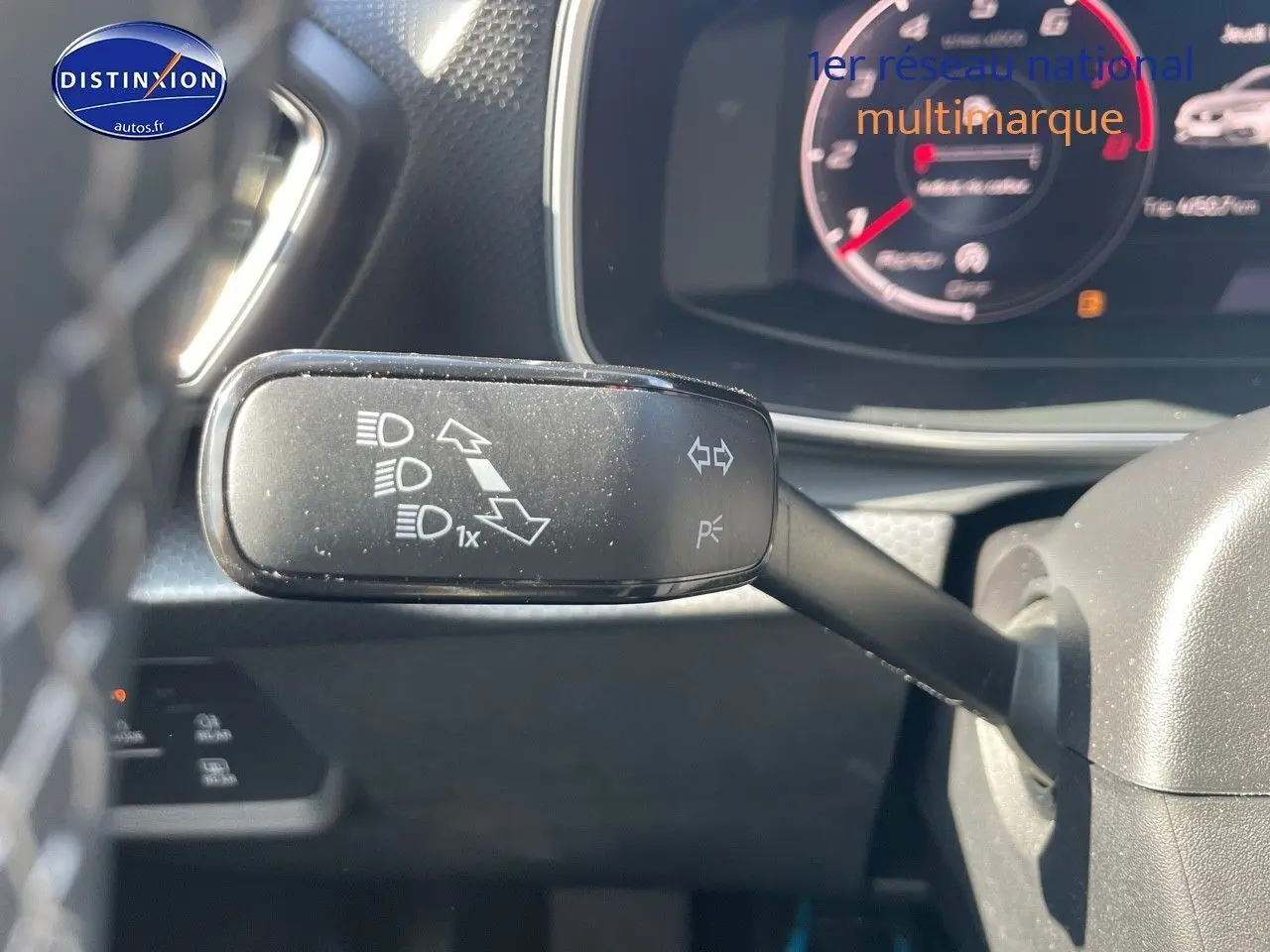 Gros plan sur la manette de clignotant à gauche du volant du SEAT LEON gris métallique, tableau de bord numérique en arrière-plan.