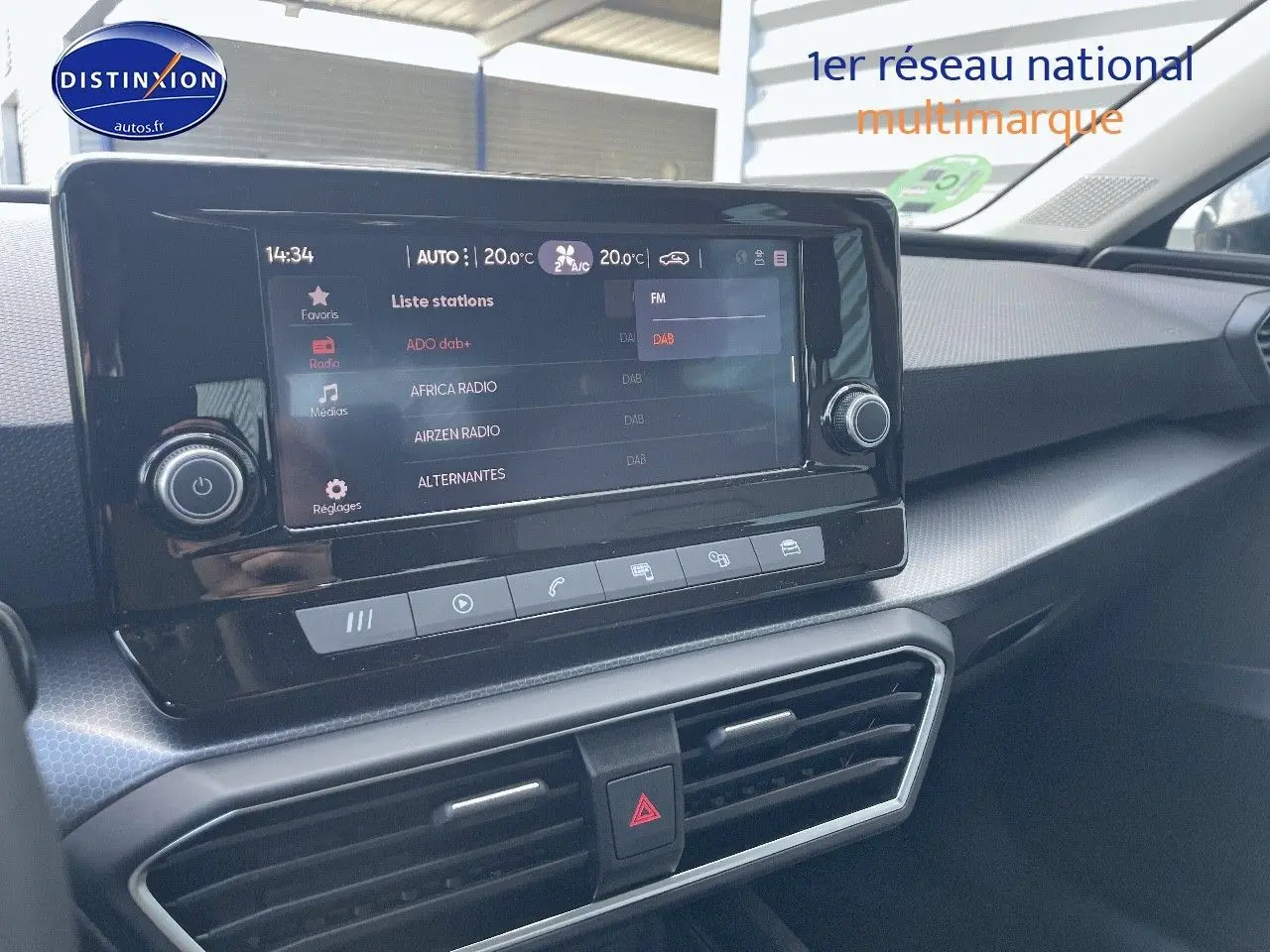 Vue intérieure du tableau de bord du SEAT Leon IV gris métallique, avec écran tactile central affichant les stations radio.