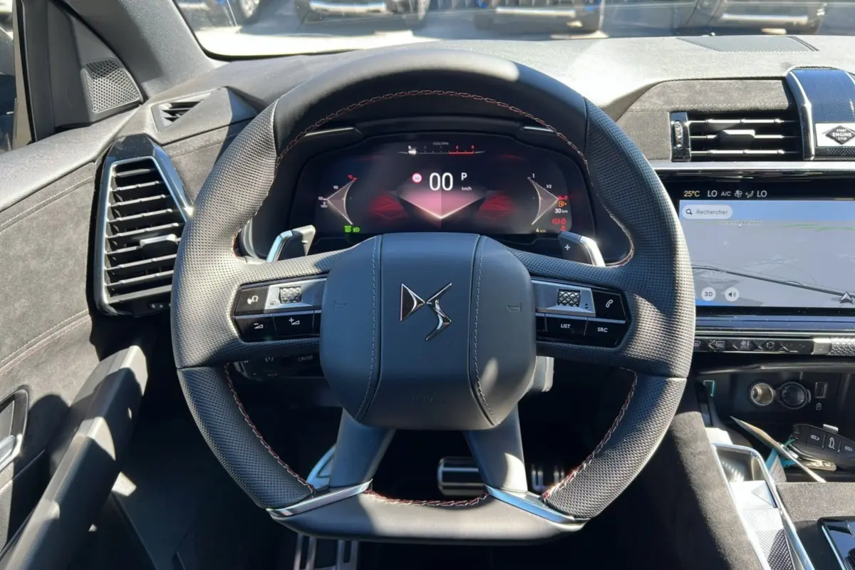 Vue centrée sur le volant du DS7 2025 gris titane, avec tableau de bord numérique et écran tactile de navigation.