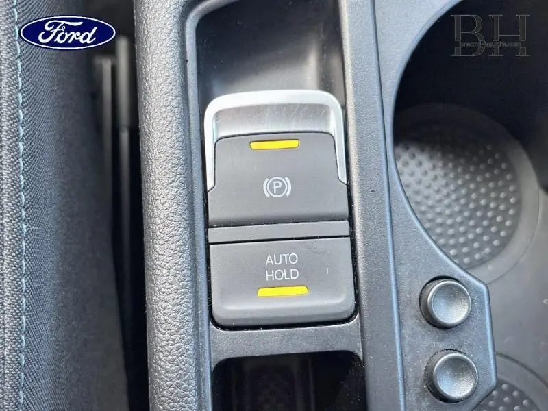 Gros plan sur la console centrale noire avec boutons frein à main électrique et fonction Auto Hold dans un Volkswagen Touran gris.