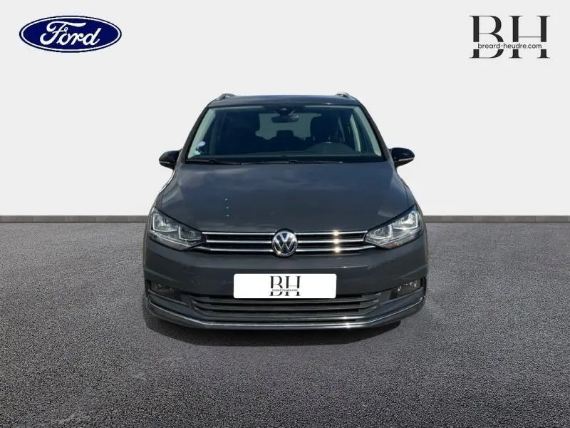 Vue de face d'un Volkswagen Touran gris Urano 2020 avec calandre chromée et phares allumés.