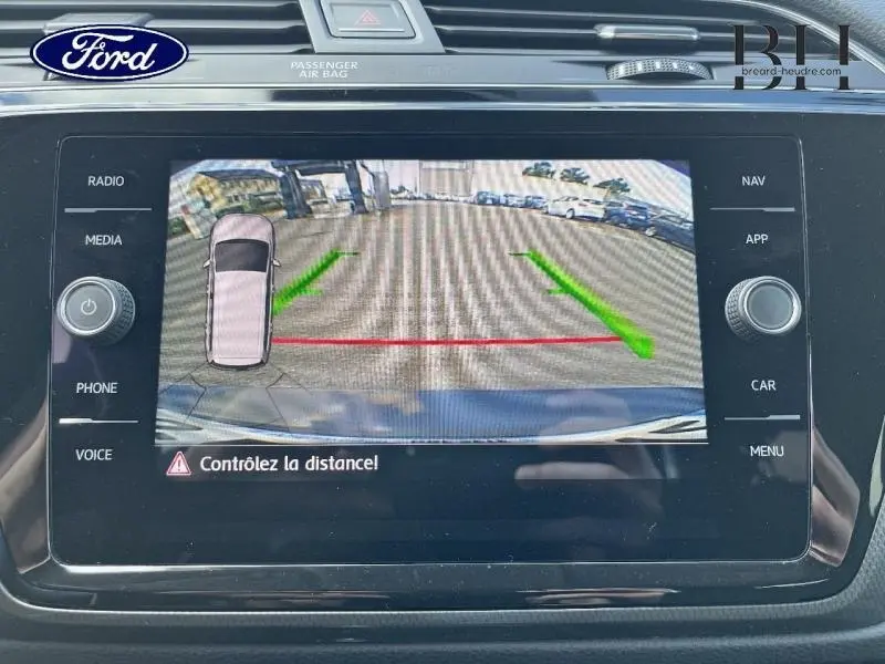 Écran tactile affichant la caméra de recul du Volkswagen Touran gris Urano, vue arrière avec lignes de guidage vertes et rouges.