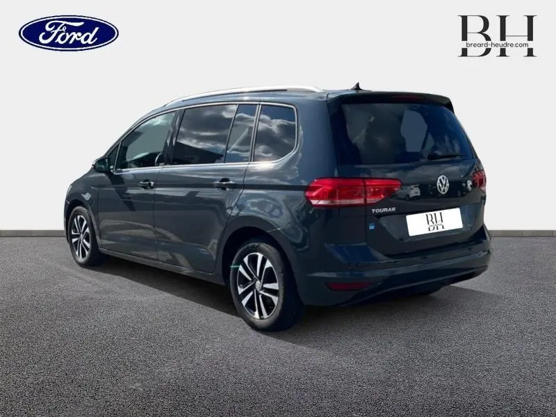 Volkswagen Touran gris Urano vu en 3/4 arrière droit, mettant en valeur ses vitres teintées et jantes alliage.