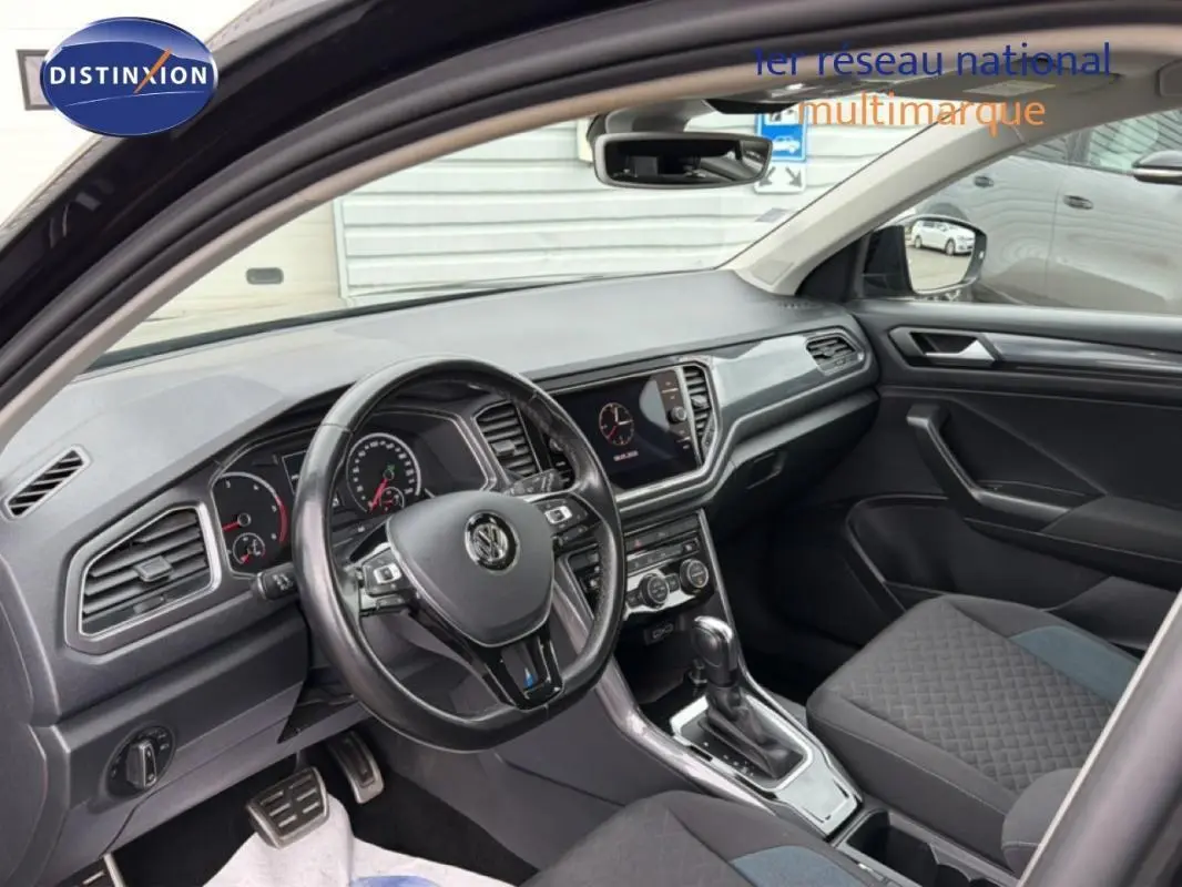 Vue intérieure côté conducteur du Volkswagen T-Roc noir 2020, avec tableau de bord moderne et volant multifonctions.