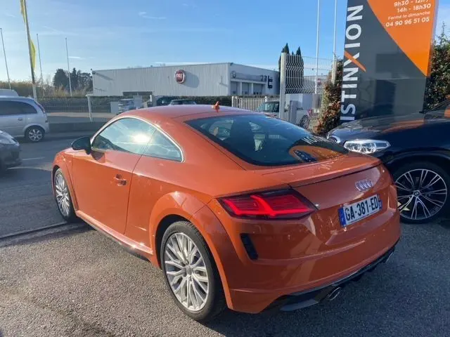 Audi TT 40 TFSI orange vue 3/4 arrière droit, avec feux LED et double sortie d’échappement visible.