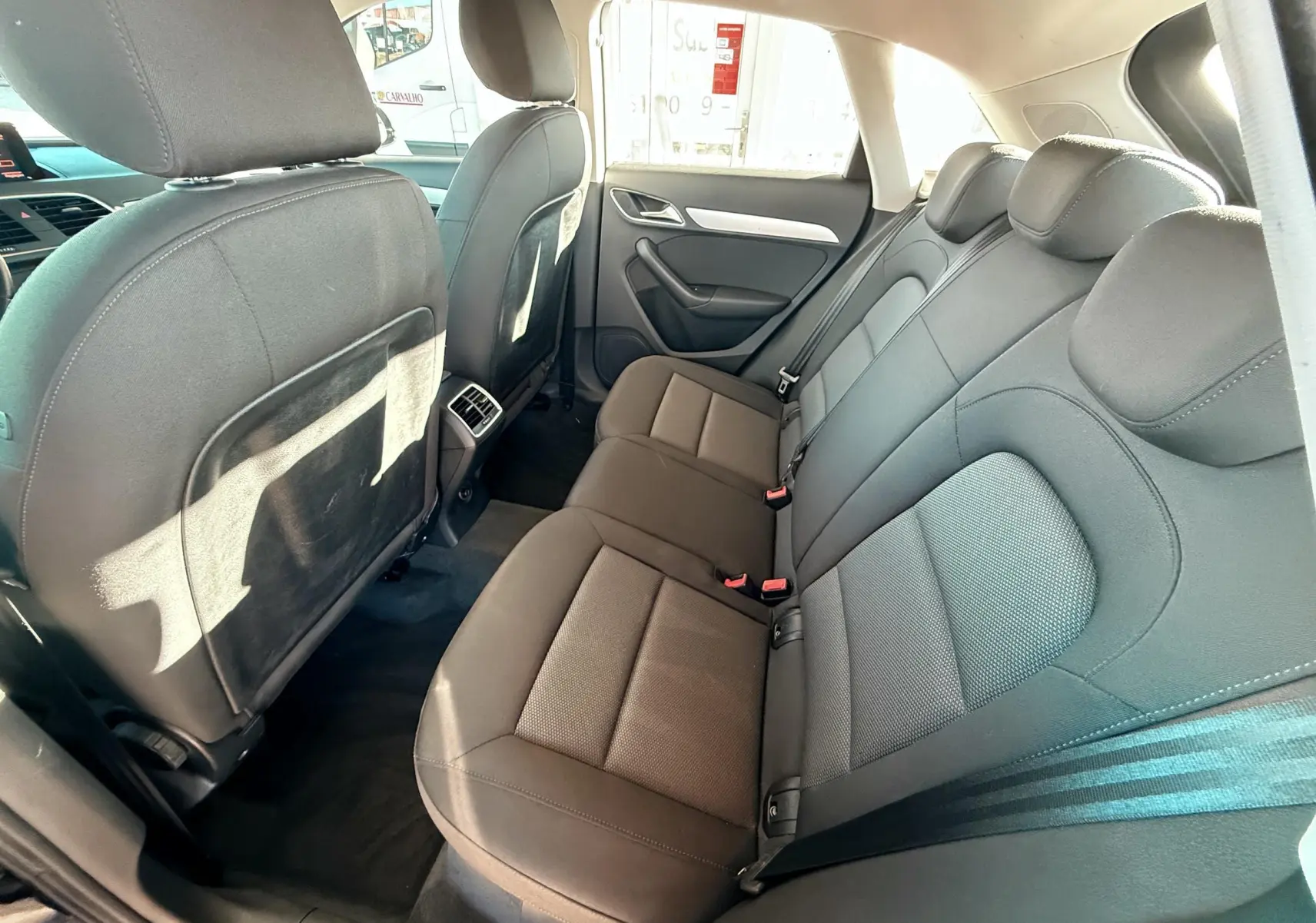 Vue intérieure des sièges arrière en tissu noir de l'Audi Q3 2016, avec appuie-têtes et ceintures visibles côté droit.