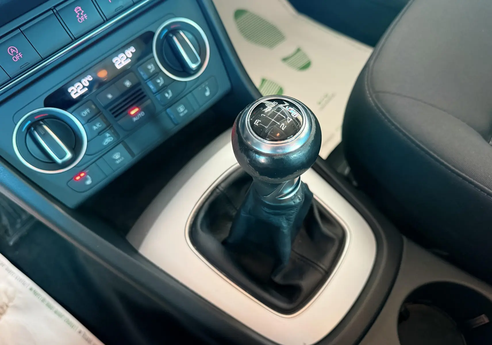 Gros plan sur le levier de vitesses manuel noir et la console centrale avec commandes de climatisation d’un Audi Q3 noir.