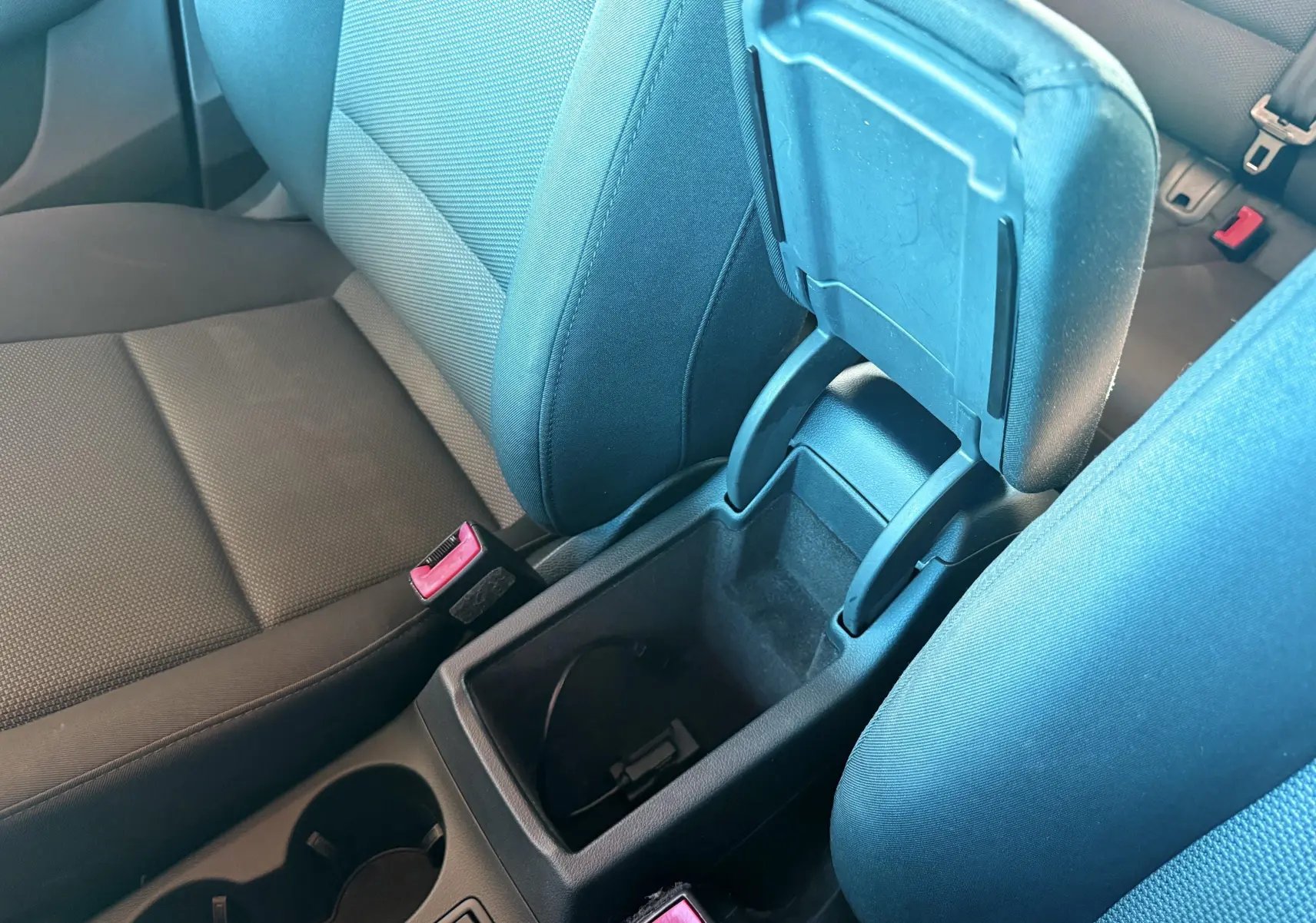 Vue intérieure centrée sur l'accoudoir ouvert et les sièges avant en tissu noir de l'Audi Q3 2016.