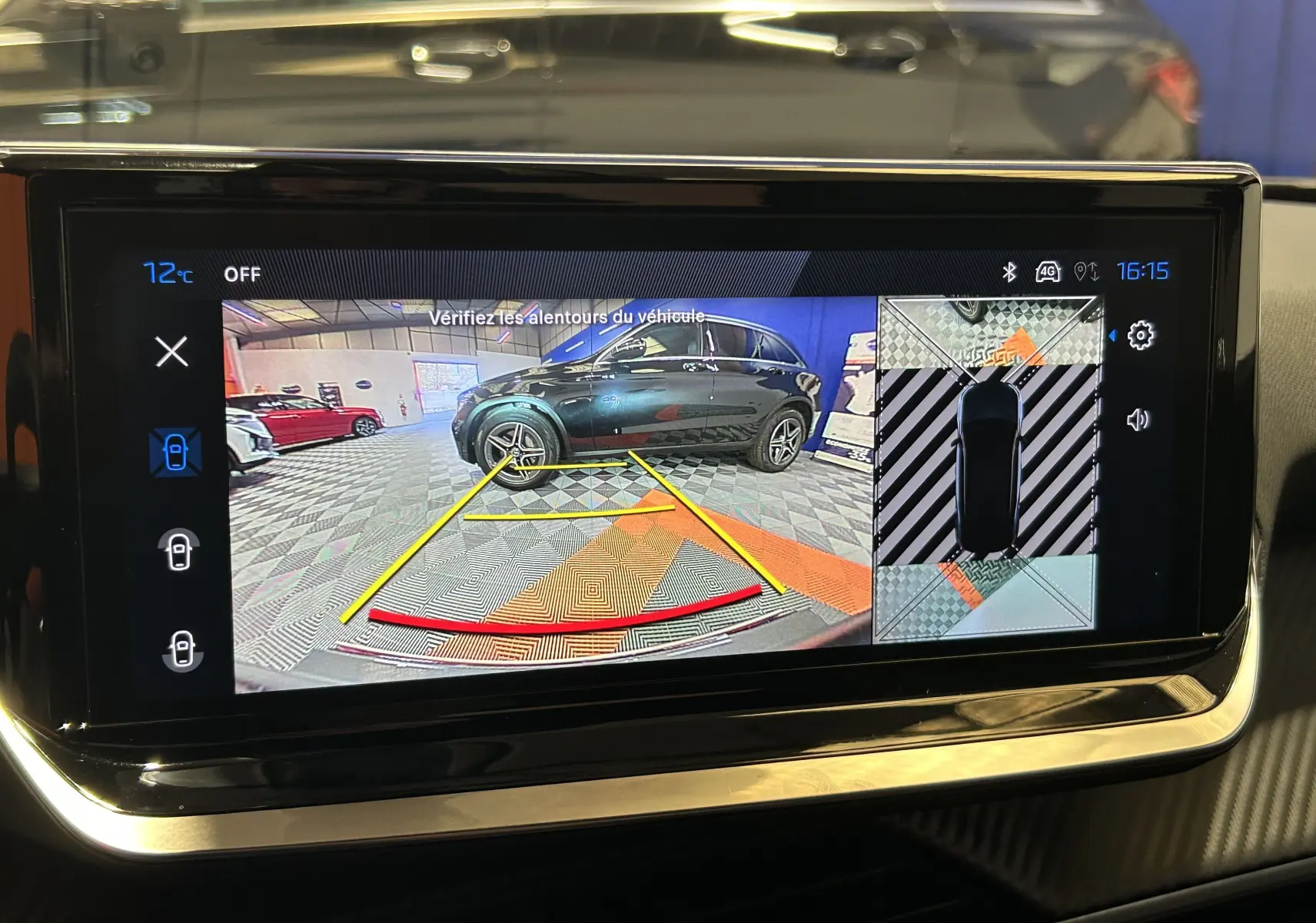 Écran de caméra de recul montrant une Peugeot 2008 bleu Obsession vue de profil droit en intérieur.