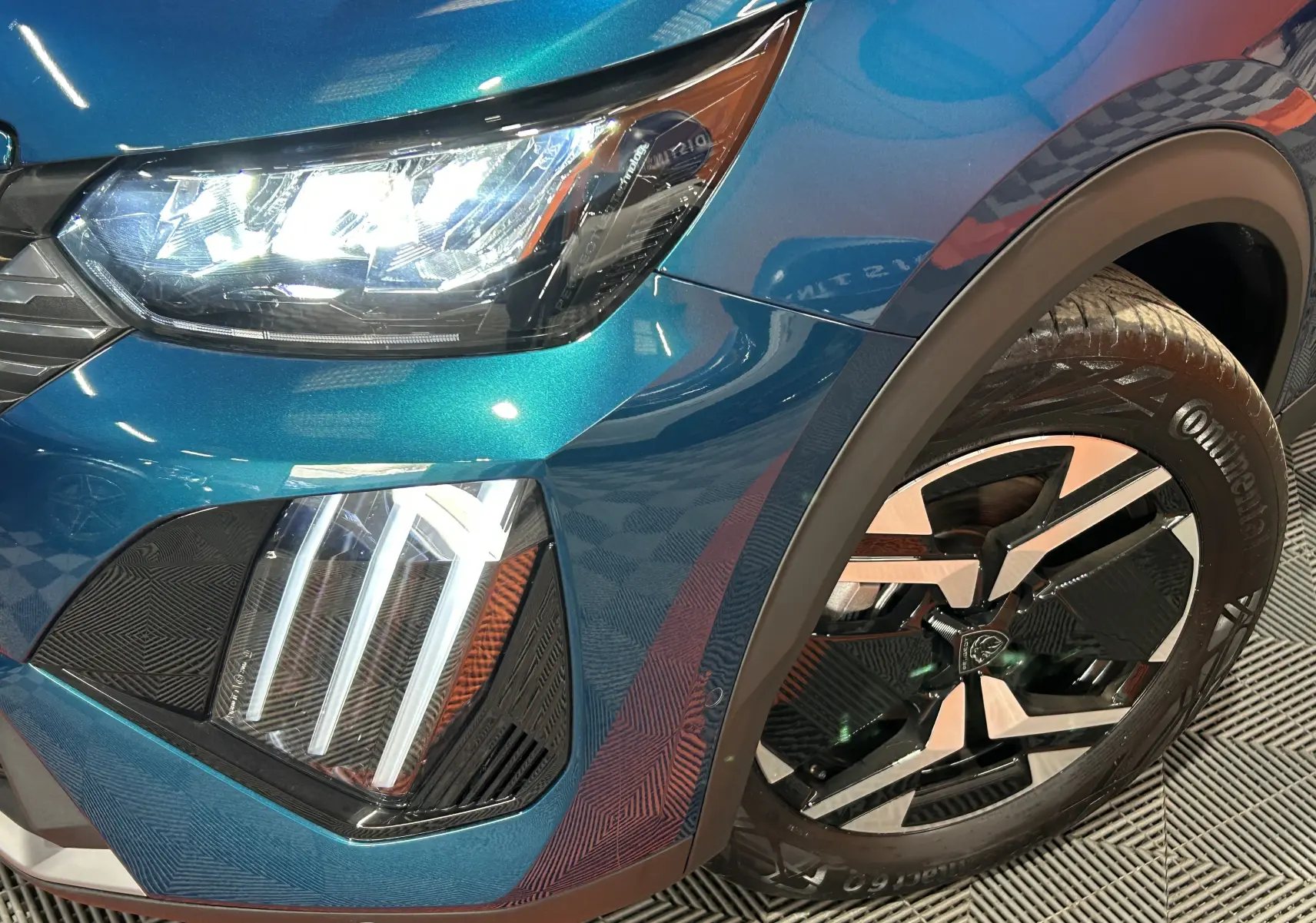 Gros plan sur l'avant droit bleu Obsession du Peugeot 2008 II Ph.2 avec phares LED allumés et jante alliage distinctive.