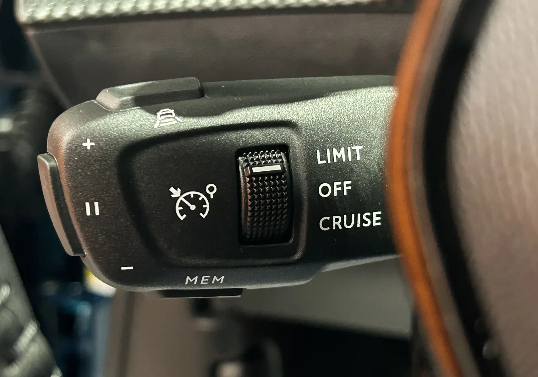 Gros plan sur la commande de régulateur de vitesse au volant du Peugeot 2008 bleu Obsession, intérieur sombre.