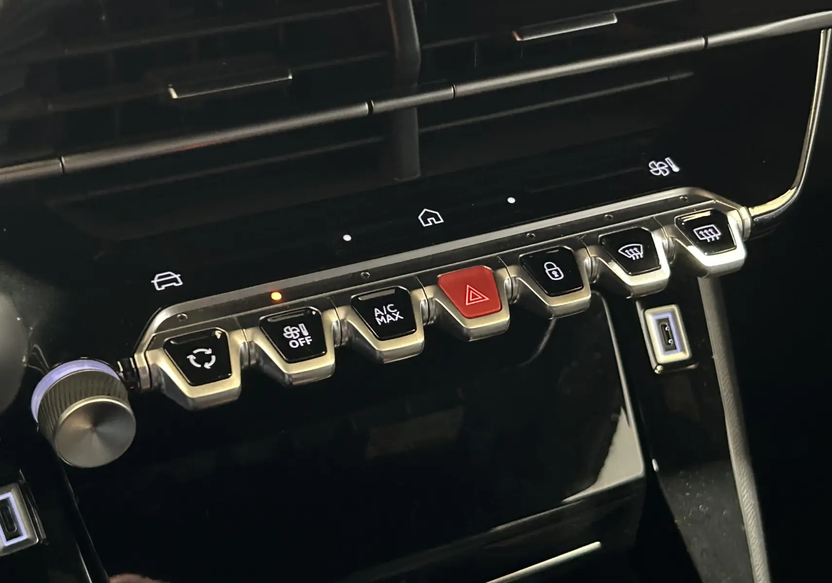 Gros plan sur la rangée de commandes métalliques du tableau de bord du Peugeot 2008 II Ph.2 Allure Hybrid 145, finition noire.