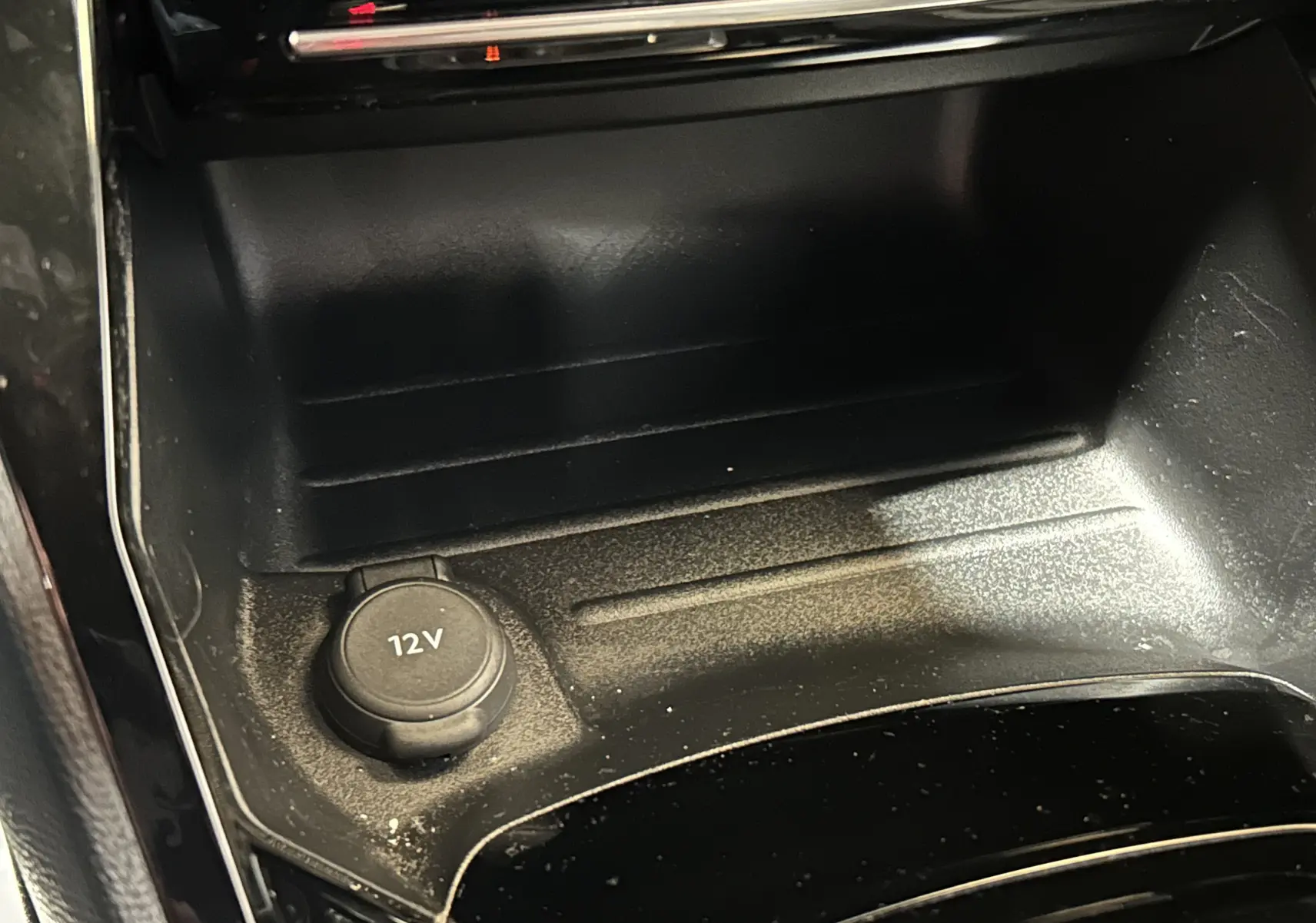 Gros plan sur la prise 12V dans la console centrale noire du Peugeot 2008 II Ph.2 Allure Hybrid 2025.