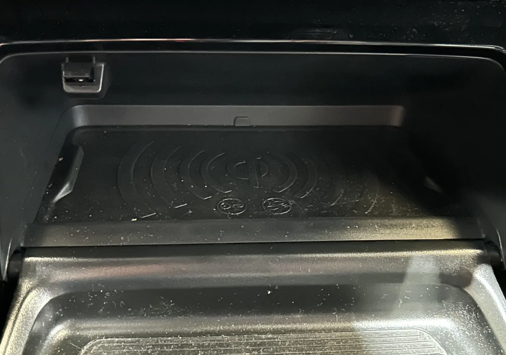 Gros plan sur le chargeur sans fil intégré dans le compartiment central du Peugeot 2008 Bleu Obsession 2025.