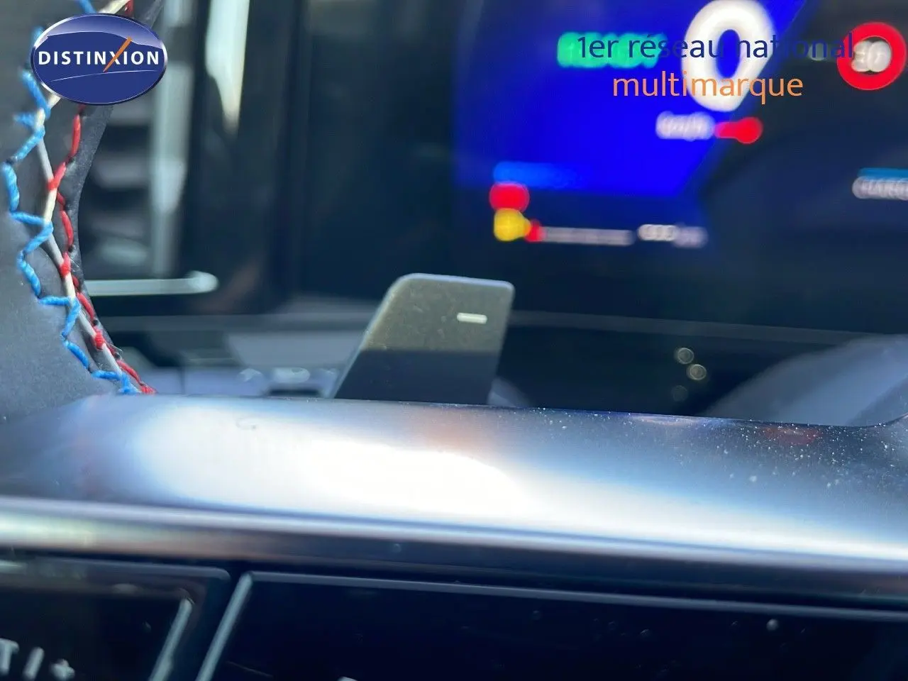 Gros plan sur le levier de vitesses automatique et le volant surpiqué bleu et rouge du Renault Espace hybride 2025.