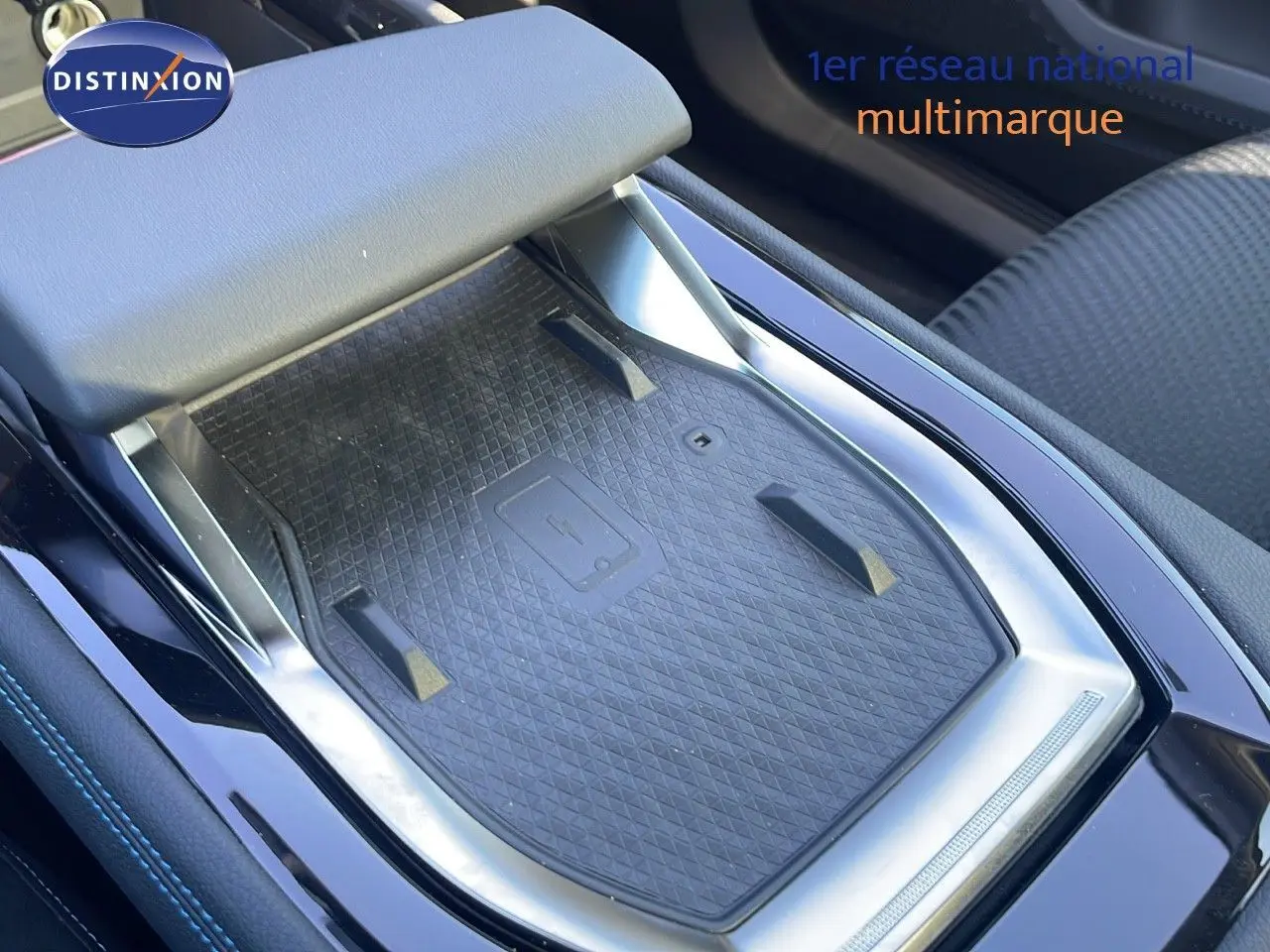 Gros plan sur la console centrale noire du Renault Espace 2025 avec tapis de recharge sans fil et accoudoir gris clair.